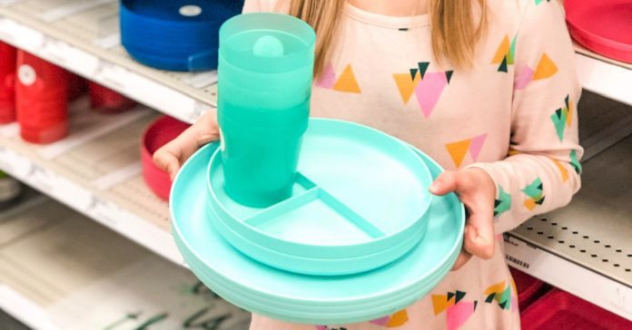 young girl holding colored plates and cups in a store