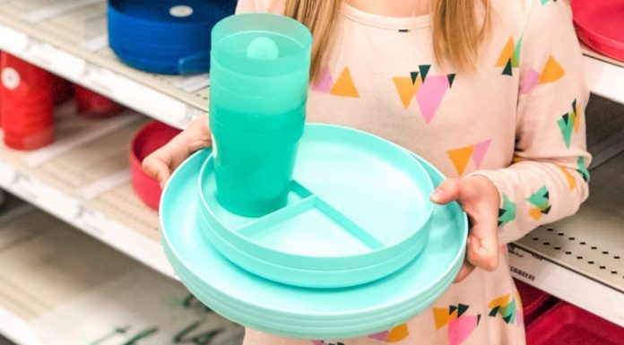 young girl holding colored plates and cups in a store