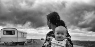 To The Parent Who Feels Lost parent holding a child in a dry land with a trailer in the background, black and white photo
