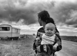 To The Parent Who Feels Lost parent holding a child in a dry land with a trailer in the background, black and white photo