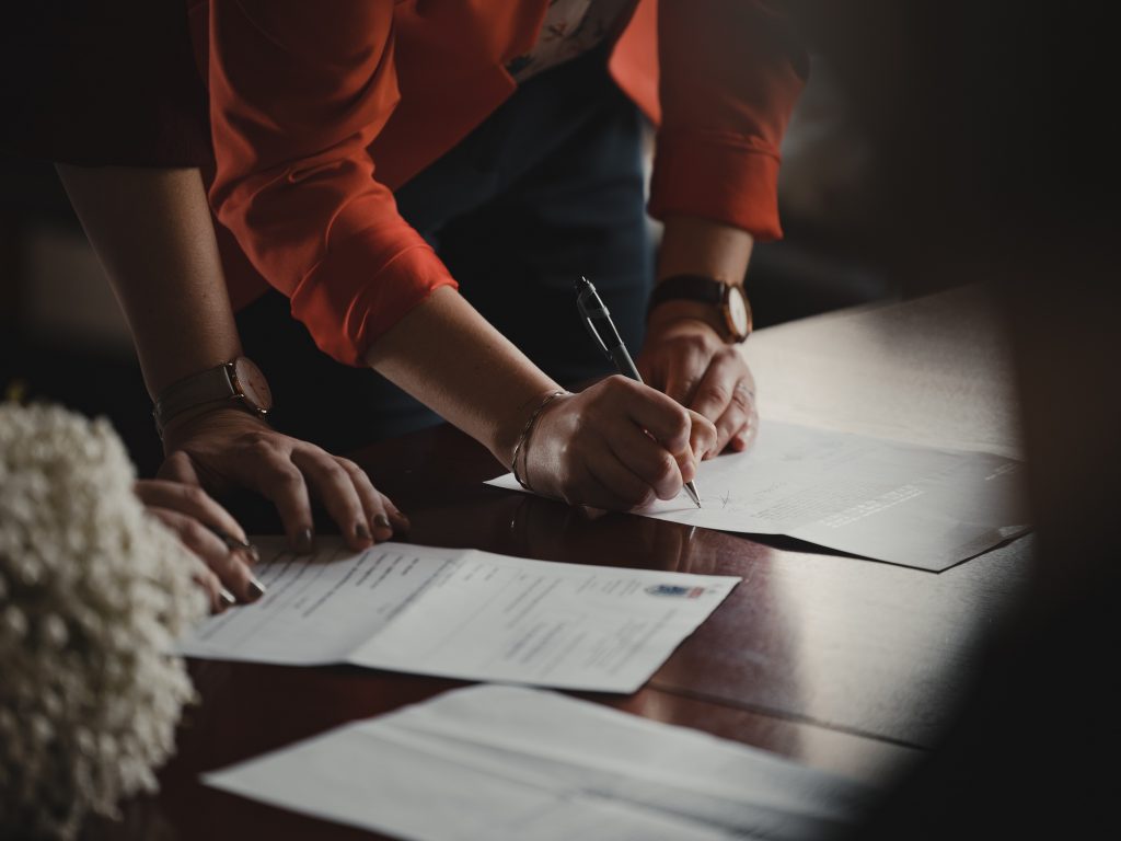 two people writing on paperwork on a table