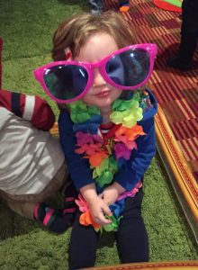 Child with oversized sunglasses and a flower garland