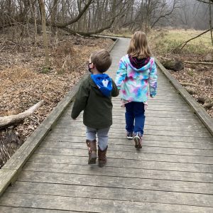 Two kids walking on a path through the woods