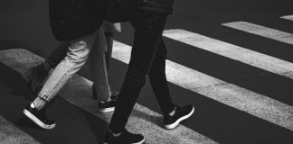 black and white photo of two people walking in a crosswalk