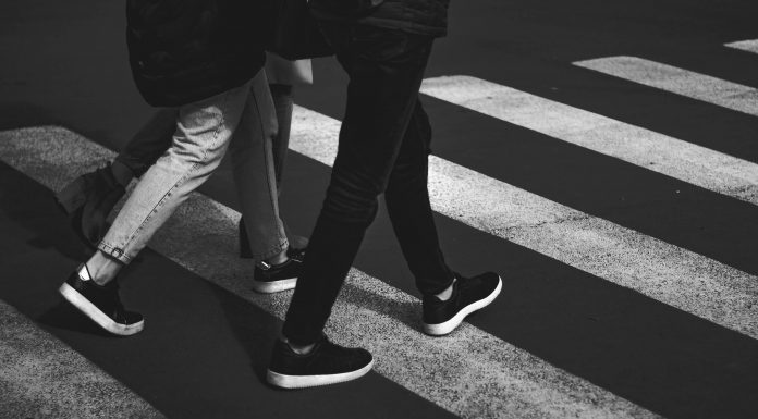 black and white photo of two people walking in a crosswalk