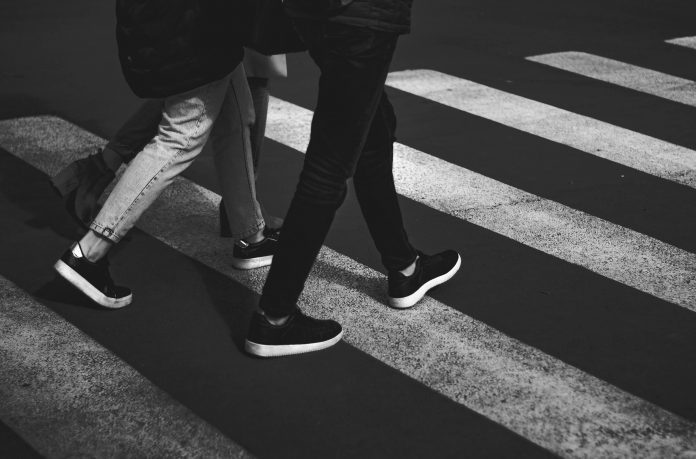 black and white photo of two people walking in a crosswalk