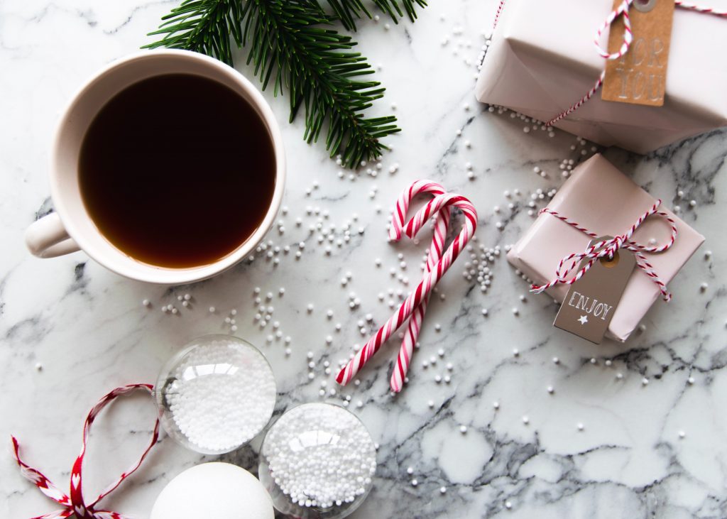 cup of tea, candy canes, wrapped gifts, and pine branch evoking a holiday feeling