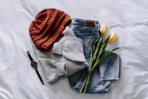 orange hat, black watch, grey sweater, blue jeans, and yellow tulips arranged all together