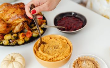 thanksgiving meal with turkey, sweet potatoes, and cranberry sauce on a white table
