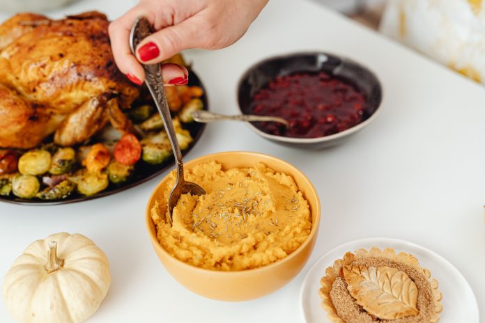 thanksgiving meal with turkey, sweet potatoes, and cranberry sauce on a white table