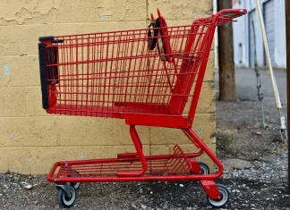 red shopping cart parked next to a yellow wall