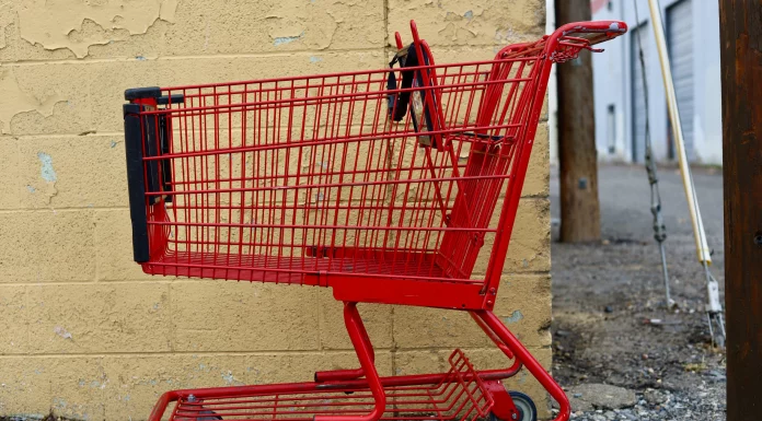 red shopping cart parked next to a yellow wall