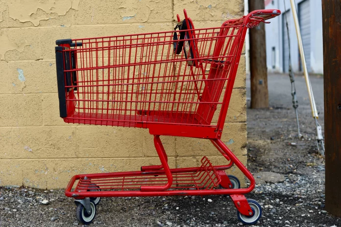 red shopping cart parked next to a yellow wall