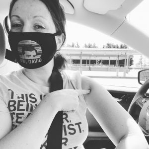 woman with a mask pointing to her vaccine injection site on arm