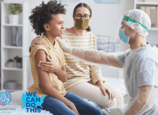 son with mother at a doctor's office holding a piece of gauze to his arm while a physician in PPE rests a hand on his shoulder, signaling comfort. We Can Do This and MMC logos in the bottom left corner