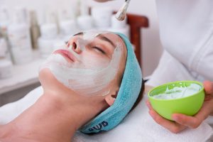 woman laying with a towel on her head receiving a facial in a spa setting