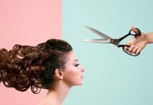 A woman is looking straight ahead while scissors are above her head