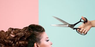 A woman is looking straight ahead while scissors are above her head