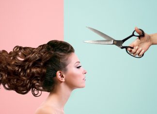 A woman is looking straight ahead while scissors are above her head