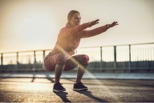 woman doing a squat with the sunshine behind her