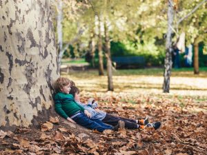 two small boys sitting under a tree outside