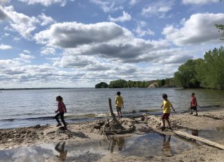 4 kids run across a beach at a lake