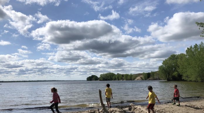 4 kids run across a beach at a lake