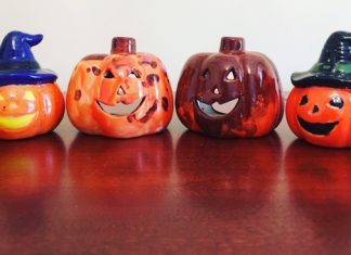 4 ceramic pumpkins are in a row. They have all been handprinted.