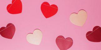 cut out hearts, which are different shades of pink and red, are shown against a light pink background.