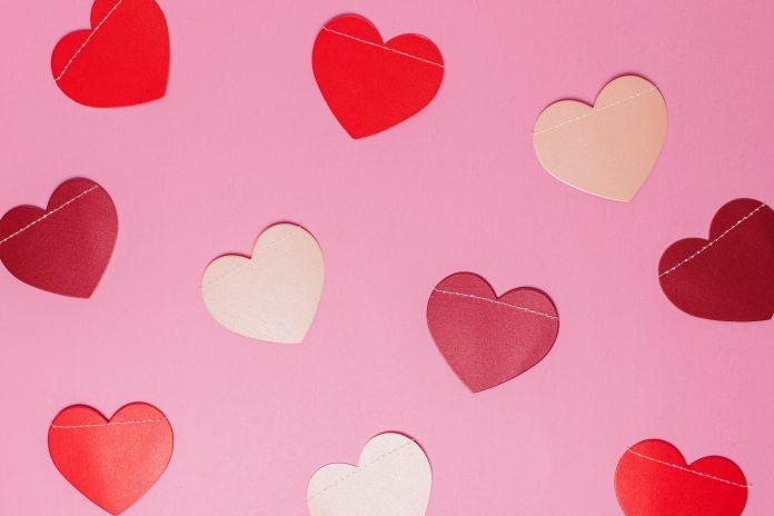 cut out hearts, which are different shades of pink and red, are shown against a light pink background.