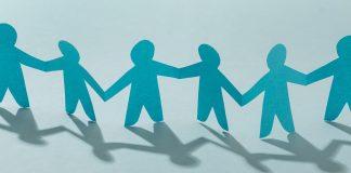 Finding Your Village A chain of blue, cut-out paper dolls, holding hands, stretches across the image.