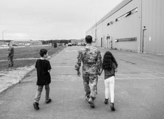 Service member and children walking away