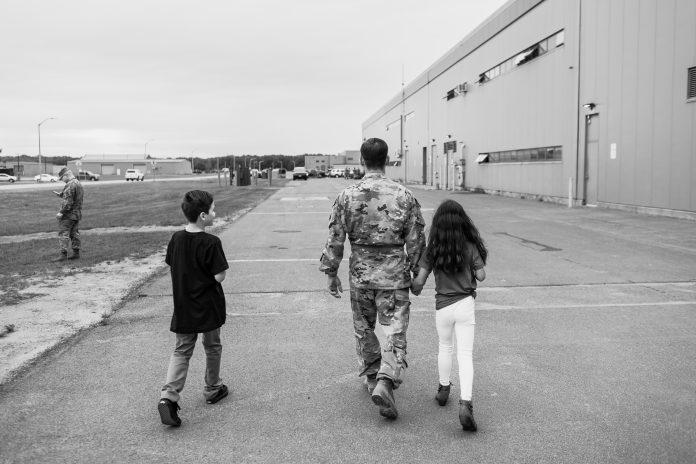 Service member and children walking away