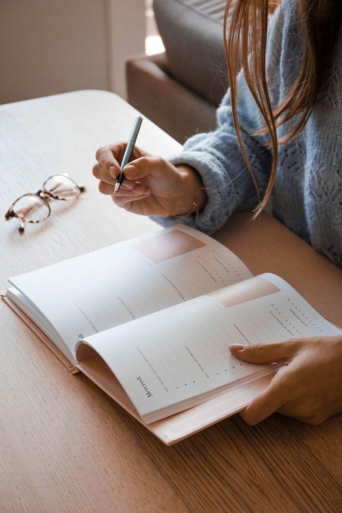 Woman writing on planner notebook