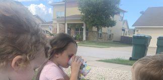 4 Ways to Increase Family Read Aloud Time Photo of three young children sitting outside on a blue blanket, drinking out of plastic cups. The book, "Sarah, Plain and Tall" is opened next to them and is being read aloud by the mother, who is not in the photo.