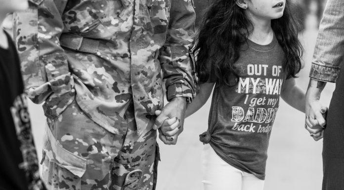 Young girl holds her dad's hand.