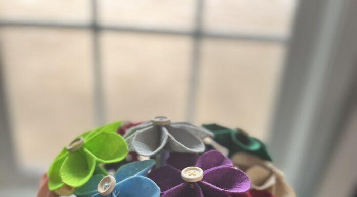 Multicolored bouquet of felt flowers with wooden button centers in a white flower pot