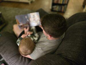 father reading a board book to child