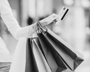 Woman holding multiple shopping bags and a credit card, representing post PCS shopping to make a new house feel like home.