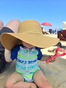 Toddler wearing floppy hat playing in the sand