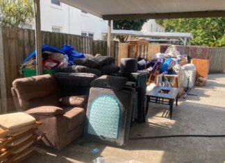 furniture pile along gate of flooded items ready for trash pickup