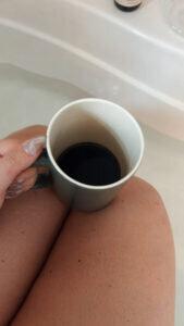 Mom sits with fresh coffee at a bathtub to reflect.