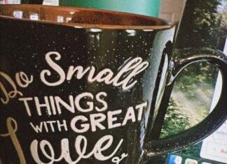 The Invisible Load of Supporting Love, Duty and Ambition A coffee mug that reads "do small things with great love" sitting next to an open laptop